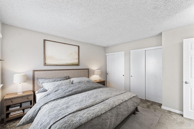 bedroom featuring multiple closets, carpet flooring, a textured ceiling, and baseboards