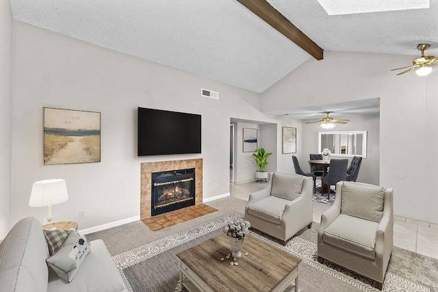 living area featuring visible vents, vaulted ceiling with beams, a textured ceiling, carpet flooring, and a fireplace