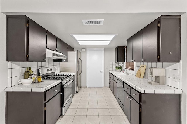 kitchen with visible vents, backsplash, gas range, under cabinet range hood, and dishwashing machine