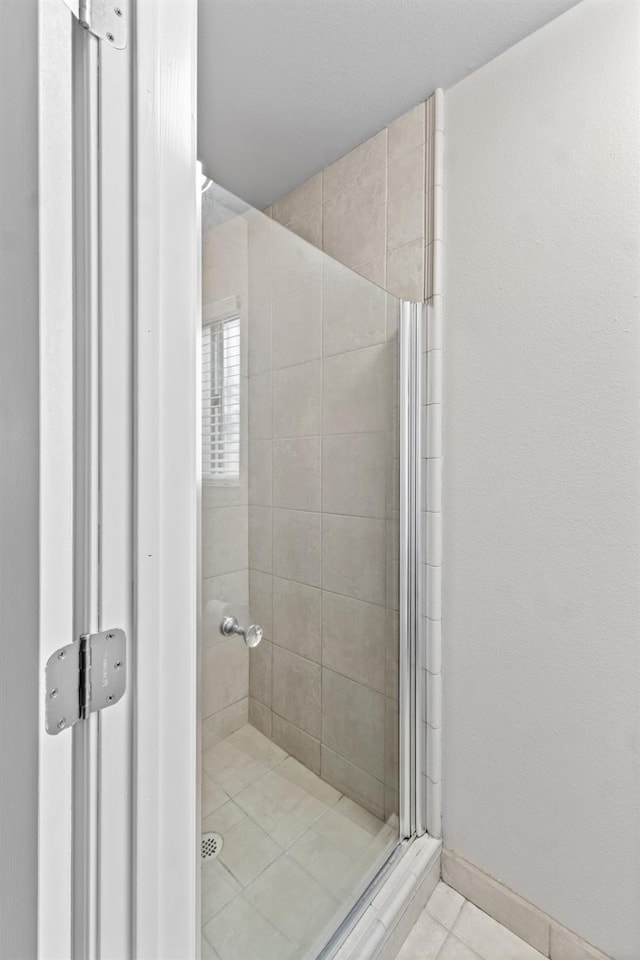 full bath with tile patterned floors, a shower stall, and baseboards