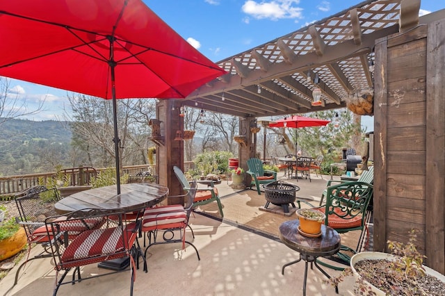 view of patio with an outdoor fire pit, outdoor dining area, and a pergola