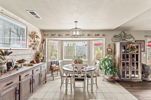 dining space with visible vents, a notable chandelier, a textured ceiling, and light tile patterned flooring