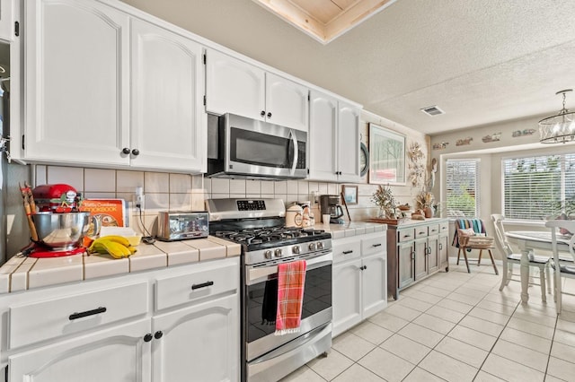 kitchen featuring tile countertops, white cabinets, and stainless steel appliances