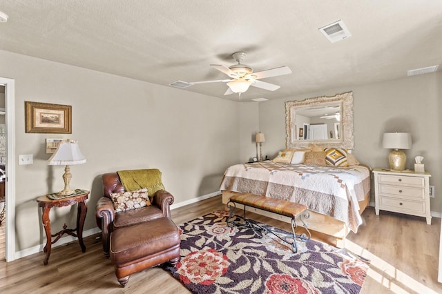 bedroom with ceiling fan, wood finished floors, visible vents, and baseboards