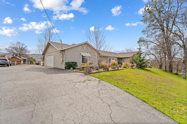 view of front of house featuring a garage, aphalt driveway, and a front lawn