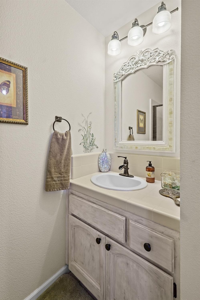 bathroom with a textured wall, vanity, and baseboards