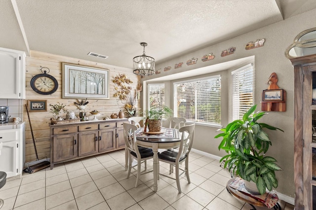 dining area featuring light tile patterned floors, visible vents, a chandelier, and a textured ceiling