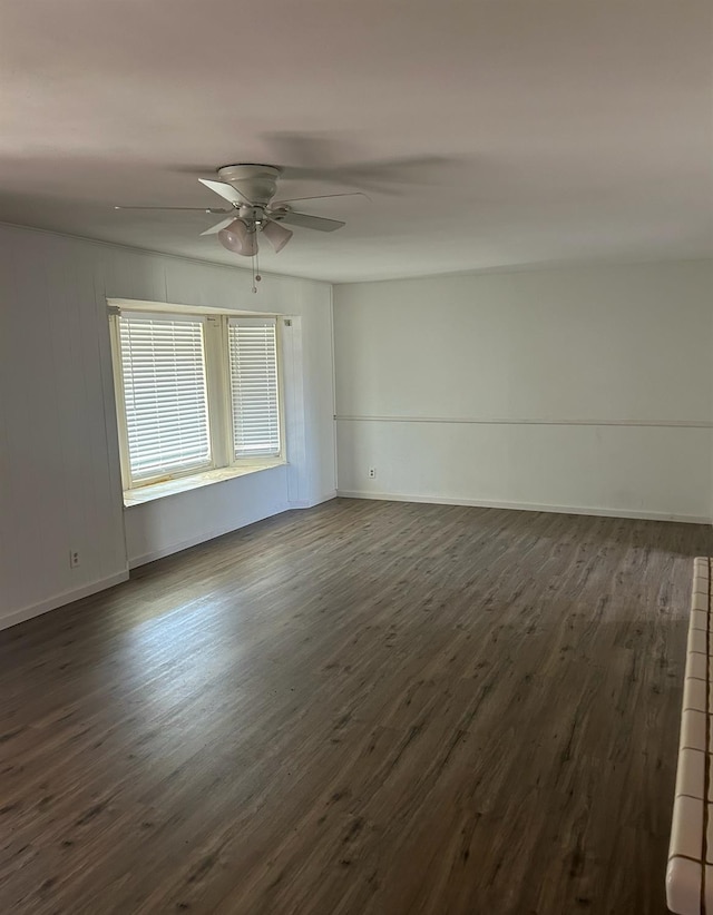 unfurnished room featuring a ceiling fan, dark wood finished floors, and baseboards