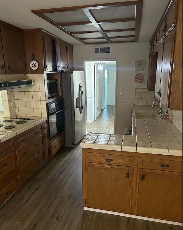 kitchen with tile countertops, stainless steel appliances, visible vents, and under cabinet range hood