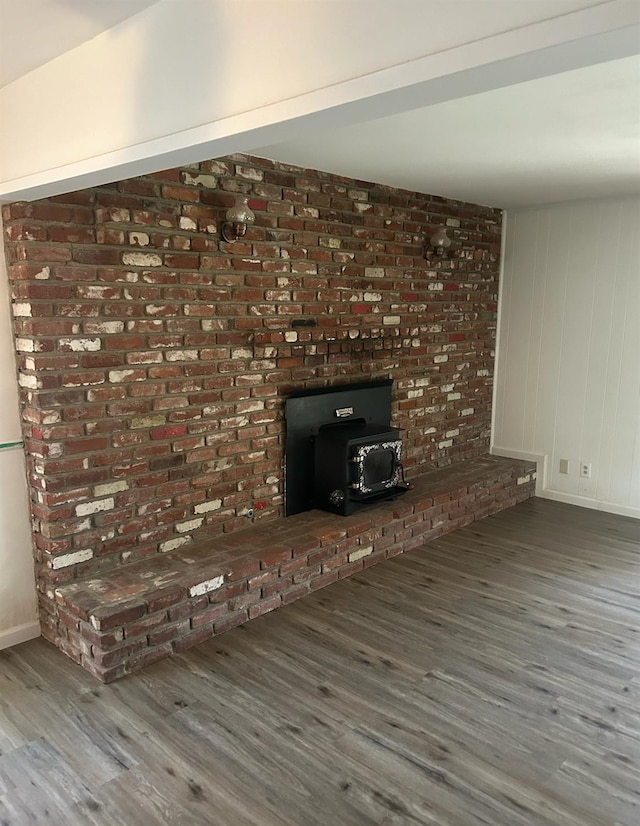 unfurnished living room with a wood stove, baseboards, and wood finished floors