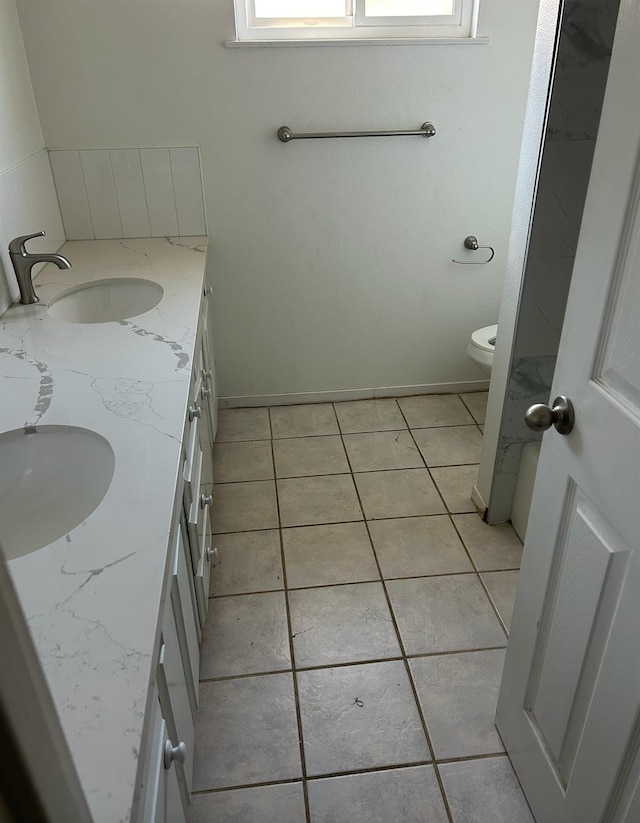 bathroom featuring double vanity, toilet, a sink, and tile patterned floors