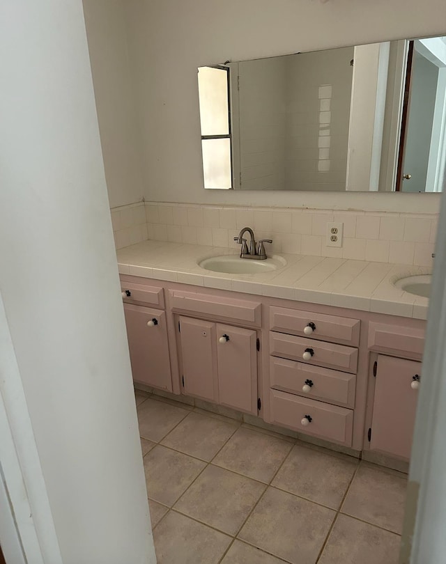 full bath featuring tile patterned flooring, a sink, backsplash, and double vanity