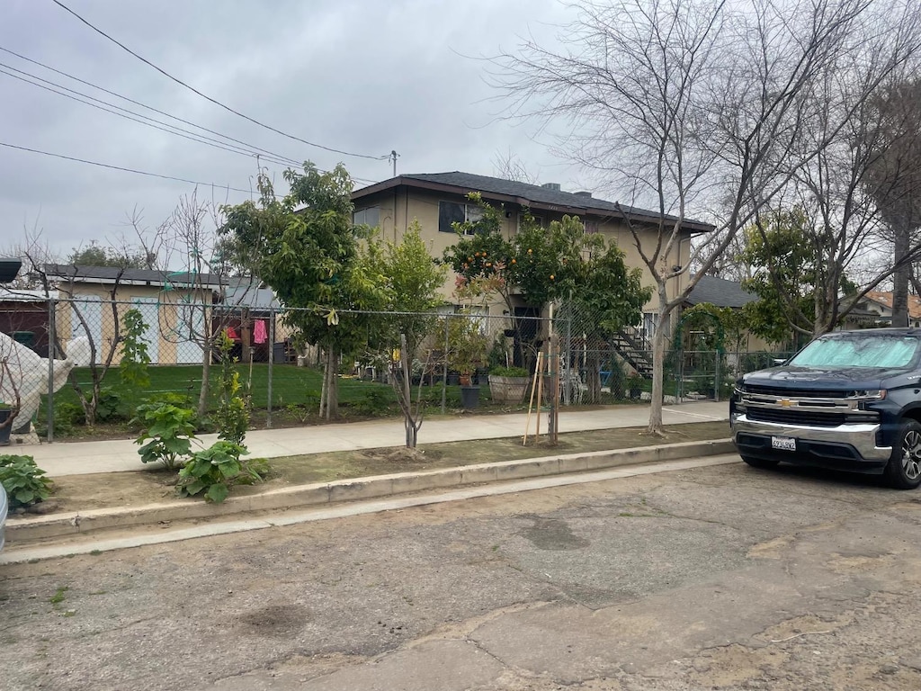 view of property hidden behind natural elements featuring a fenced front yard and stucco siding