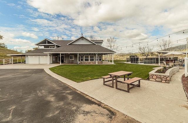 view of front of property featuring a shingled roof, concrete driveway, covered porch, an attached garage, and a front lawn