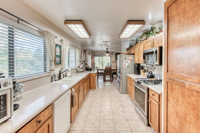 kitchen featuring a sink, backsplash, appliances with stainless steel finishes, light countertops, and light tile patterned floors