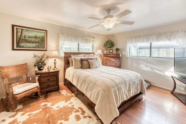 bedroom featuring hardwood / wood-style flooring, multiple windows, and baseboards