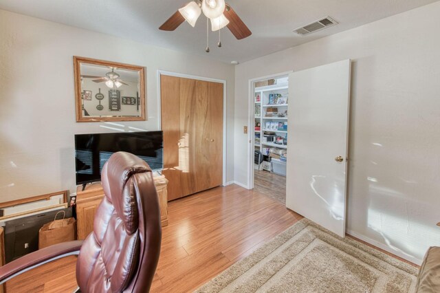 home office with a ceiling fan, wood finished floors, and visible vents