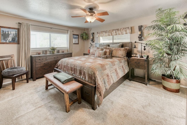 bedroom featuring light colored carpet, a textured ceiling, and ceiling fan