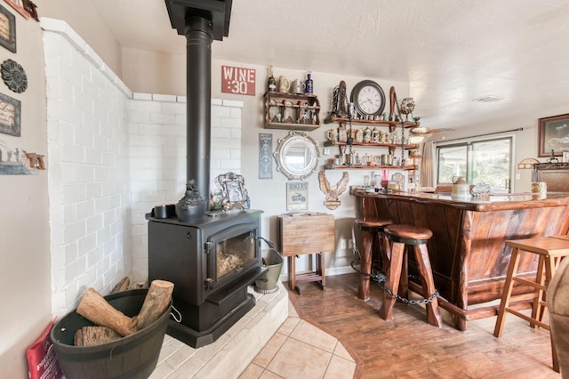 bar featuring tile patterned floors, visible vents, a bar, and a wood stove