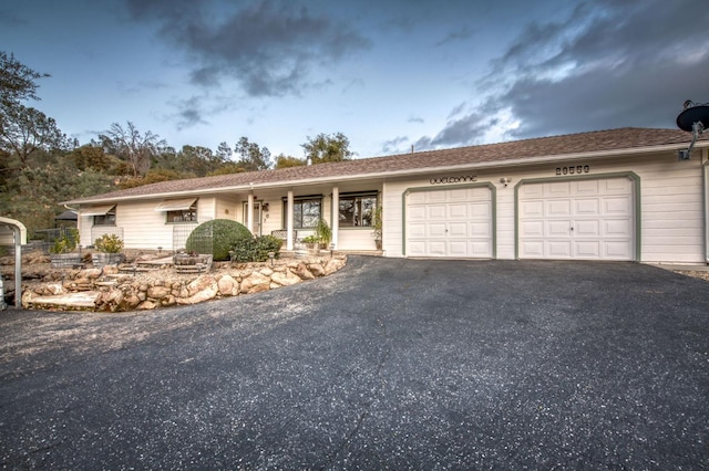 single story home with aphalt driveway and an attached garage