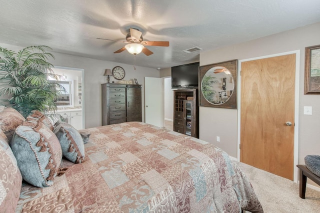 bedroom with visible vents, multiple closets, a textured ceiling, carpet floors, and ceiling fan