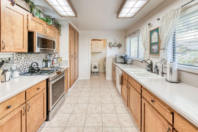 kitchen with tasteful backsplash, light countertops, light tile patterned floors, appliances with stainless steel finishes, and a sink