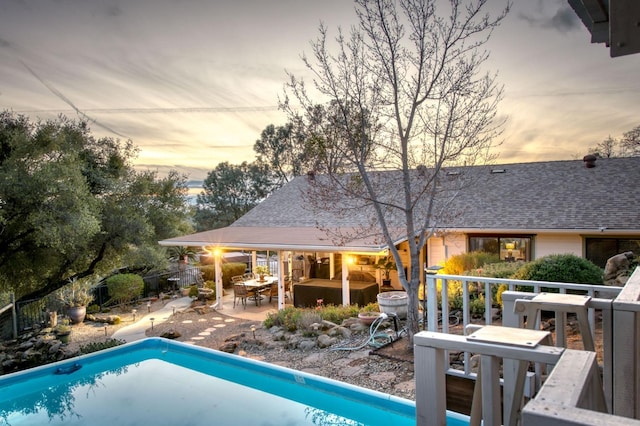 pool at dusk featuring an outdoor pool, outdoor dining area, a patio, and fence