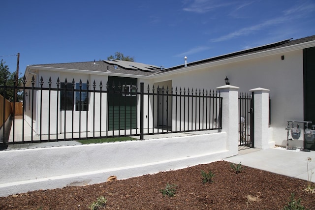 view of gate featuring a fenced front yard and roof mounted solar panels