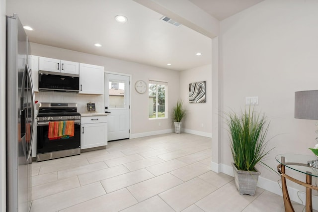 kitchen with visible vents, white cabinets, light countertops, appliances with stainless steel finishes, and backsplash