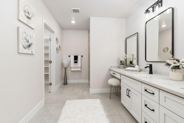 full bathroom with a walk in closet, visible vents, vanity, baseboards, and tile patterned floors