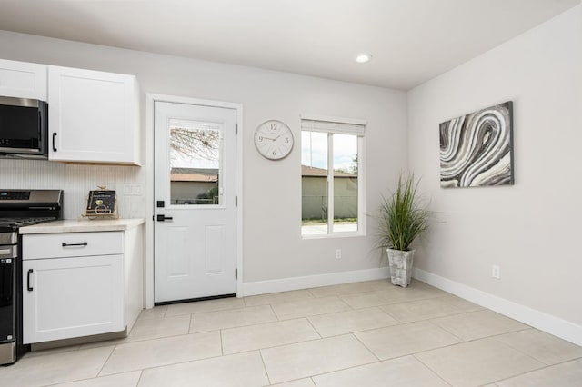 kitchen featuring stainless steel appliances, white cabinetry, baseboards, light countertops, and tasteful backsplash