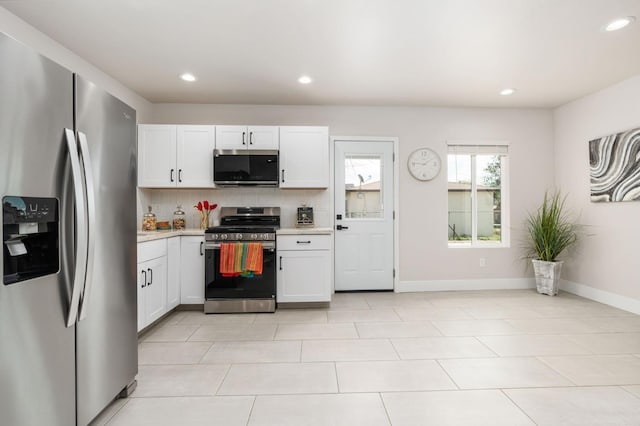 kitchen with tasteful backsplash, baseboards, white cabinets, stainless steel appliances, and light countertops