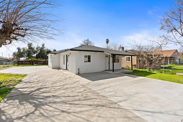 view of front facade featuring concrete driveway, fence, a front lawn, and stucco siding