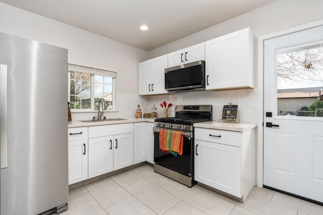 kitchen with backsplash, stainless steel appliances, a sink, and light countertops