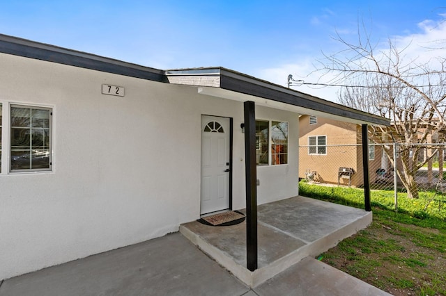 property entrance featuring fence and stucco siding