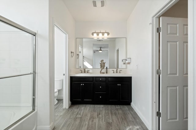 bathroom with toilet, double vanity, a sink, and wood finished floors