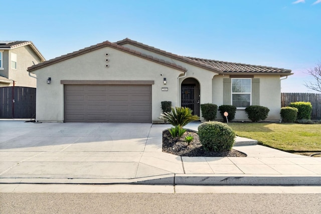 mediterranean / spanish home with stucco siding, concrete driveway, an attached garage, fence, and a tiled roof