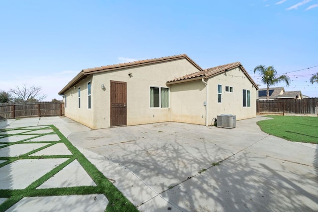 back of house with stucco siding, a fenced backyard, central AC, and a patio