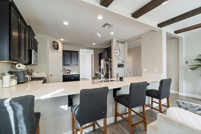 kitchen with visible vents, beamed ceiling, a peninsula, stainless steel appliances, and light wood-style floors