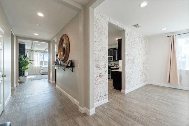 hall featuring light wood finished floors, plenty of natural light, and visible vents