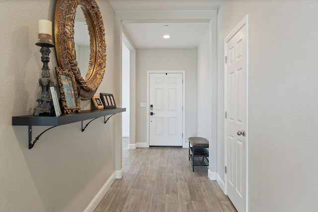 corridor featuring light wood-type flooring and baseboards