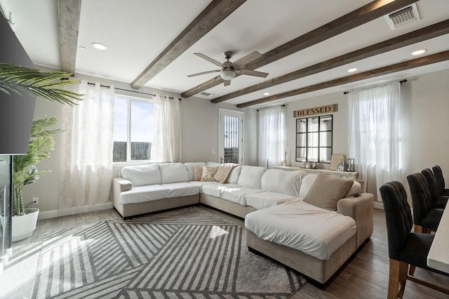 living room with visible vents, beamed ceiling, baseboards, and wood finished floors