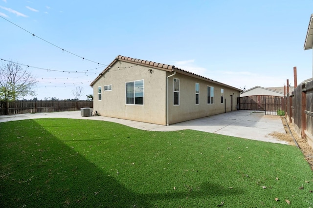 rear view of house featuring a patio, a fenced backyard, cooling unit, a yard, and stucco siding