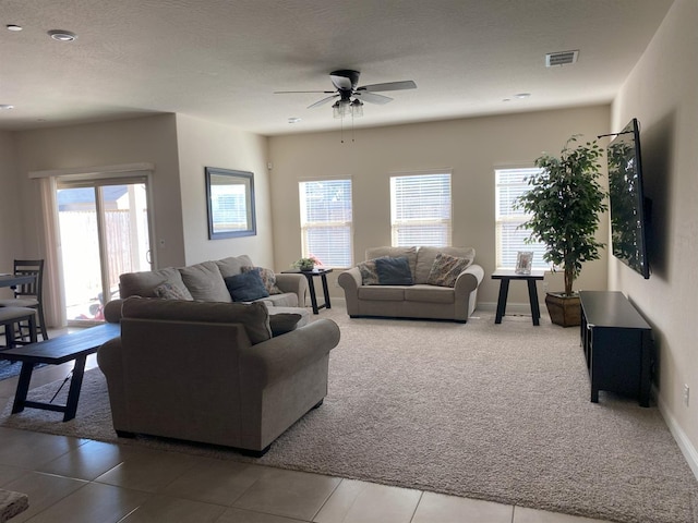 carpeted living room with baseboards, visible vents, ceiling fan, and a textured ceiling