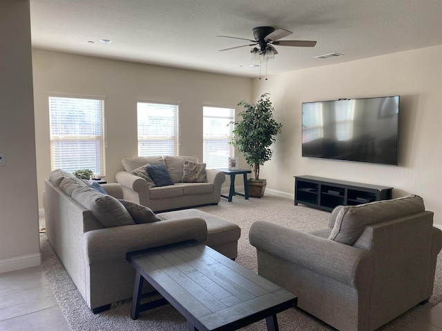 living room with baseboards, visible vents, and a ceiling fan