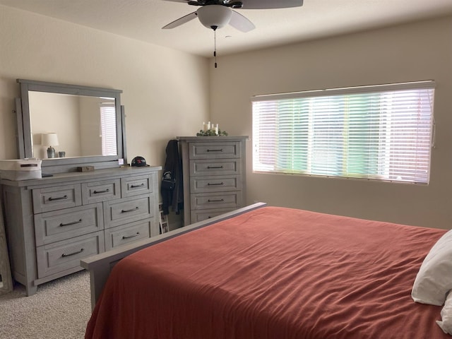 bedroom with multiple windows, a ceiling fan, and light colored carpet