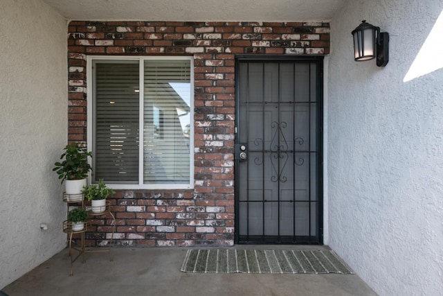 property entrance featuring brick siding and stucco siding