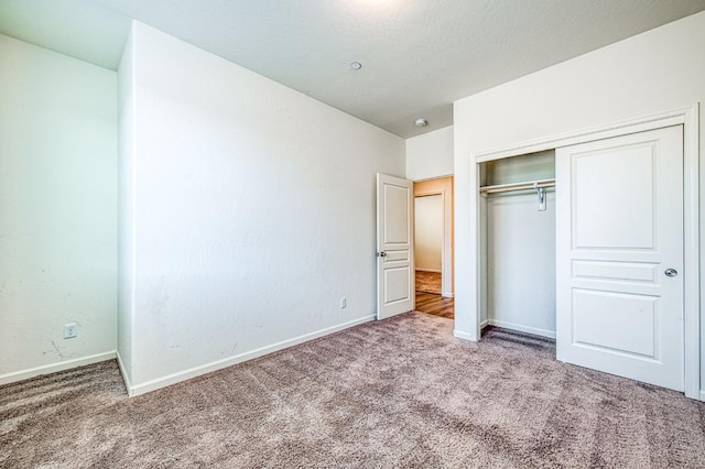 unfurnished bedroom with carpet, a closet, and baseboards