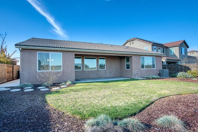 rear view of property with a patio, a tile roof, fence, a yard, and stucco siding