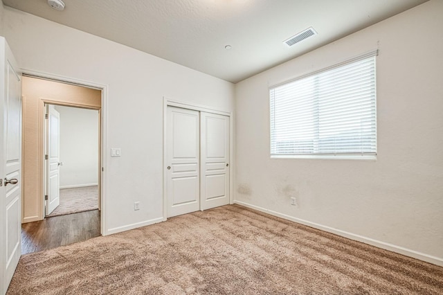 unfurnished bedroom featuring a closet, baseboards, visible vents, and carpet flooring